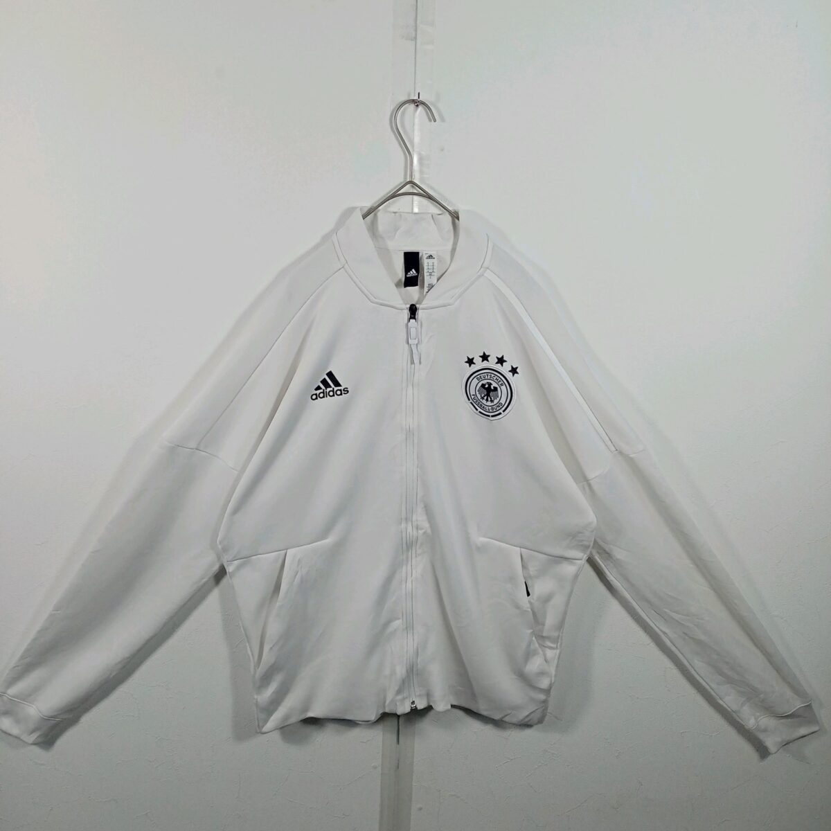 ドイツ代表のadidas製トラックジャケット（白）の正面。胸にadidasのロゴとDFBのエンブレム、4つの星